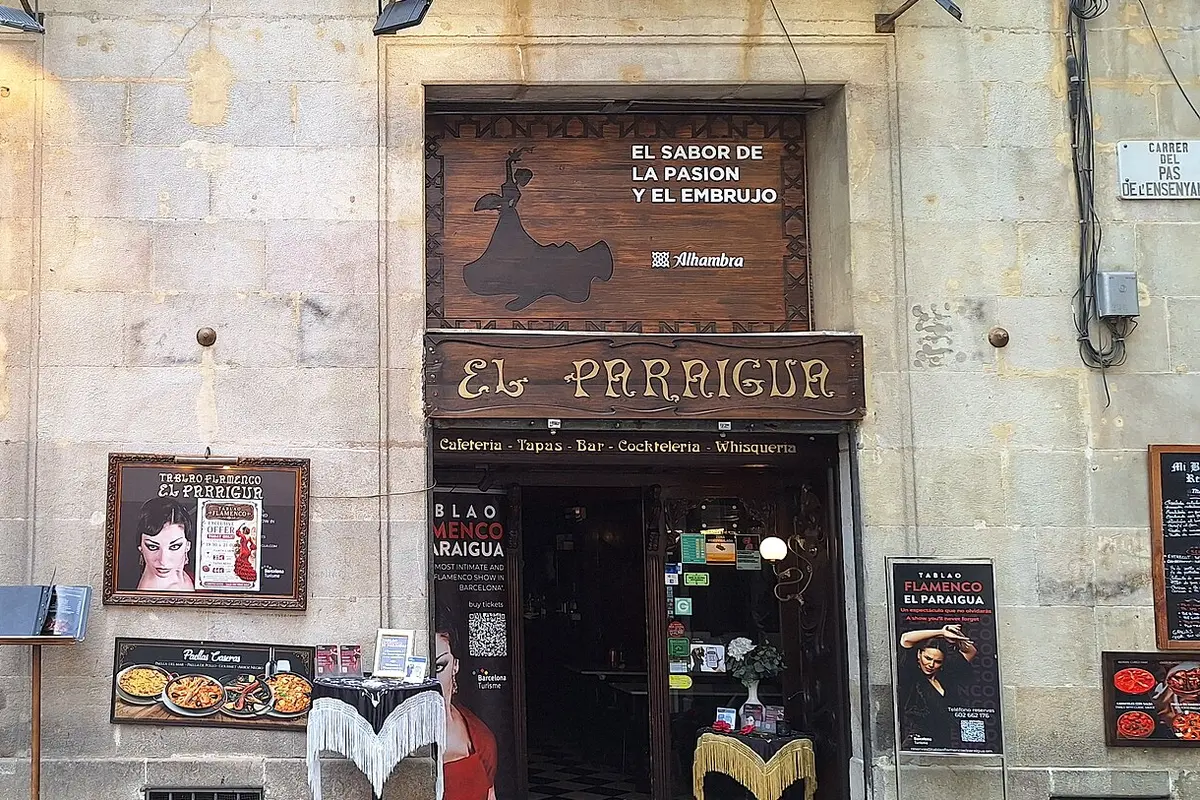 The street-level entrance of El Paraigua, with a carved wooden sign above the door and posters for the flamenco tablao
